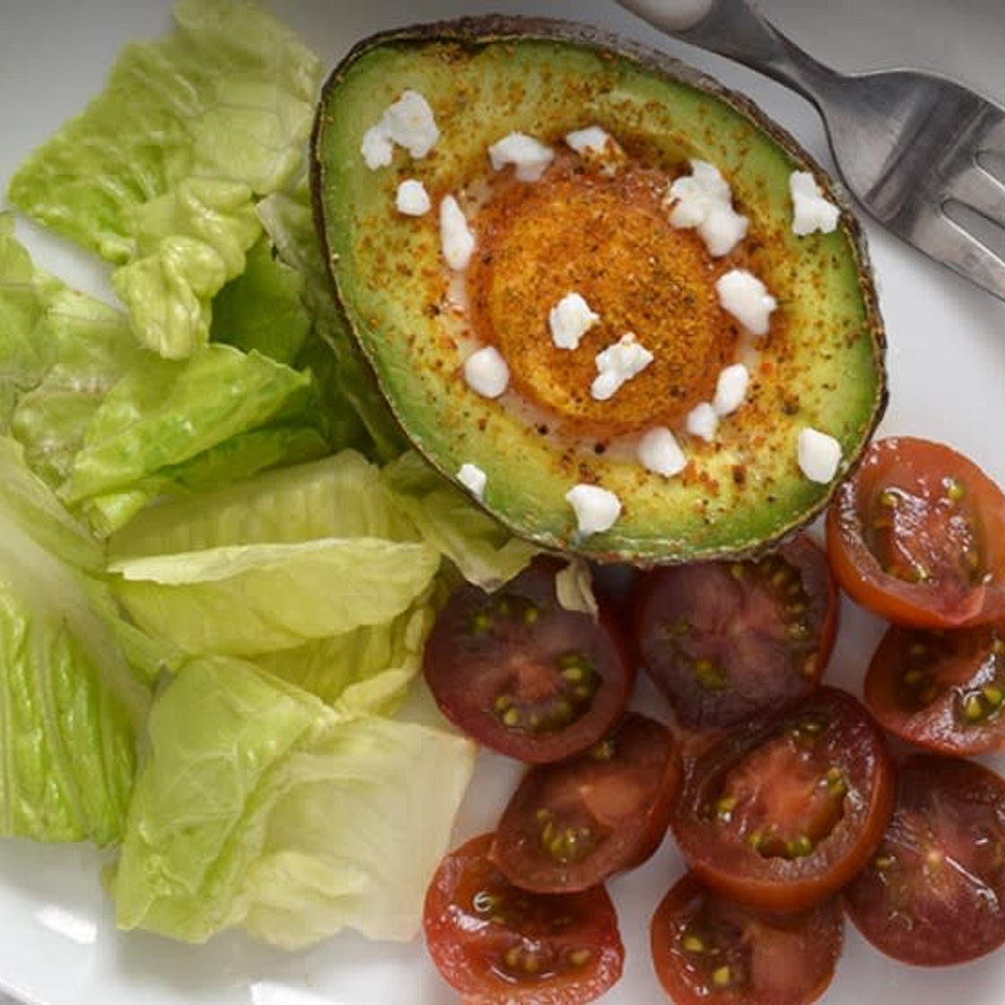 Huevos al horno sobre aguacate con queso de cabra.