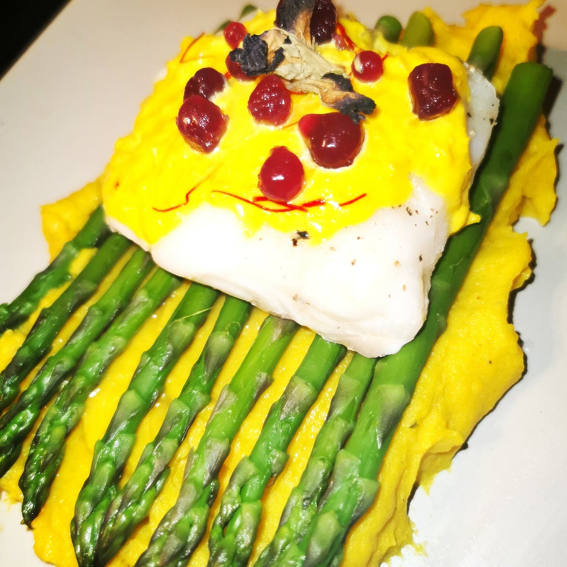 Asparagus with cod and saffron sauce with butterfly pea flower jellies laid on a bed of curry potato mash