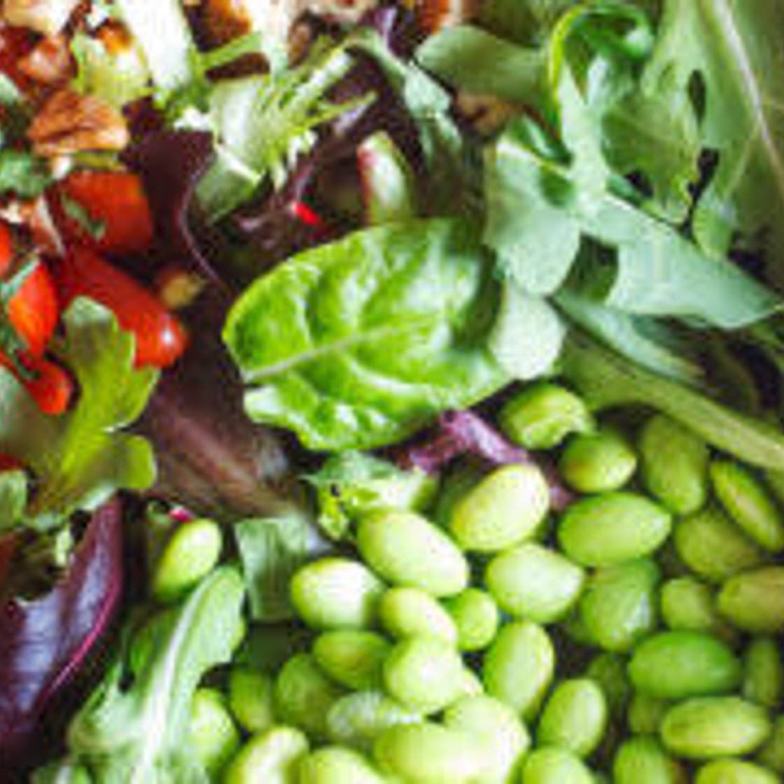 Salad with lettuce, arugula, tomatoes, green onions, edamame, and seedy ranch dressing