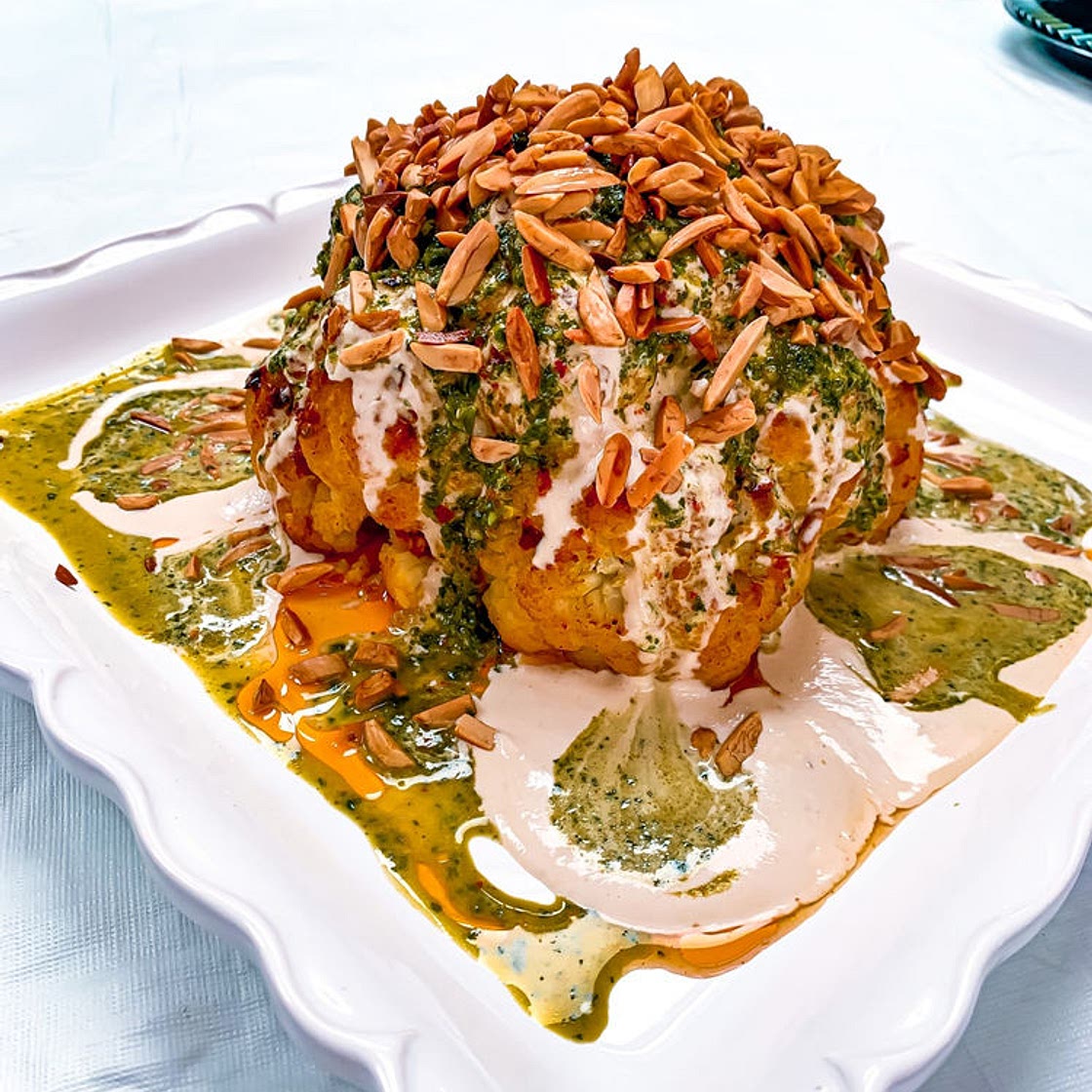 SPICY ROASTED WHOLE CAULIFLOWER WITH CILANTRO SAUCE, TAHINI SAUCE & CRUNCHY ALMONDS