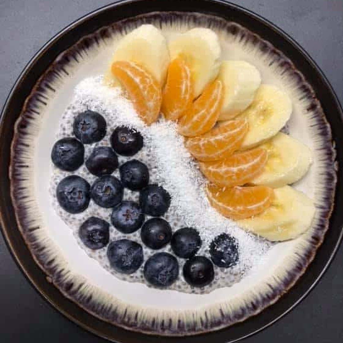 Chia seeds pudding with blueberries, banana, clementine and coconut flakes