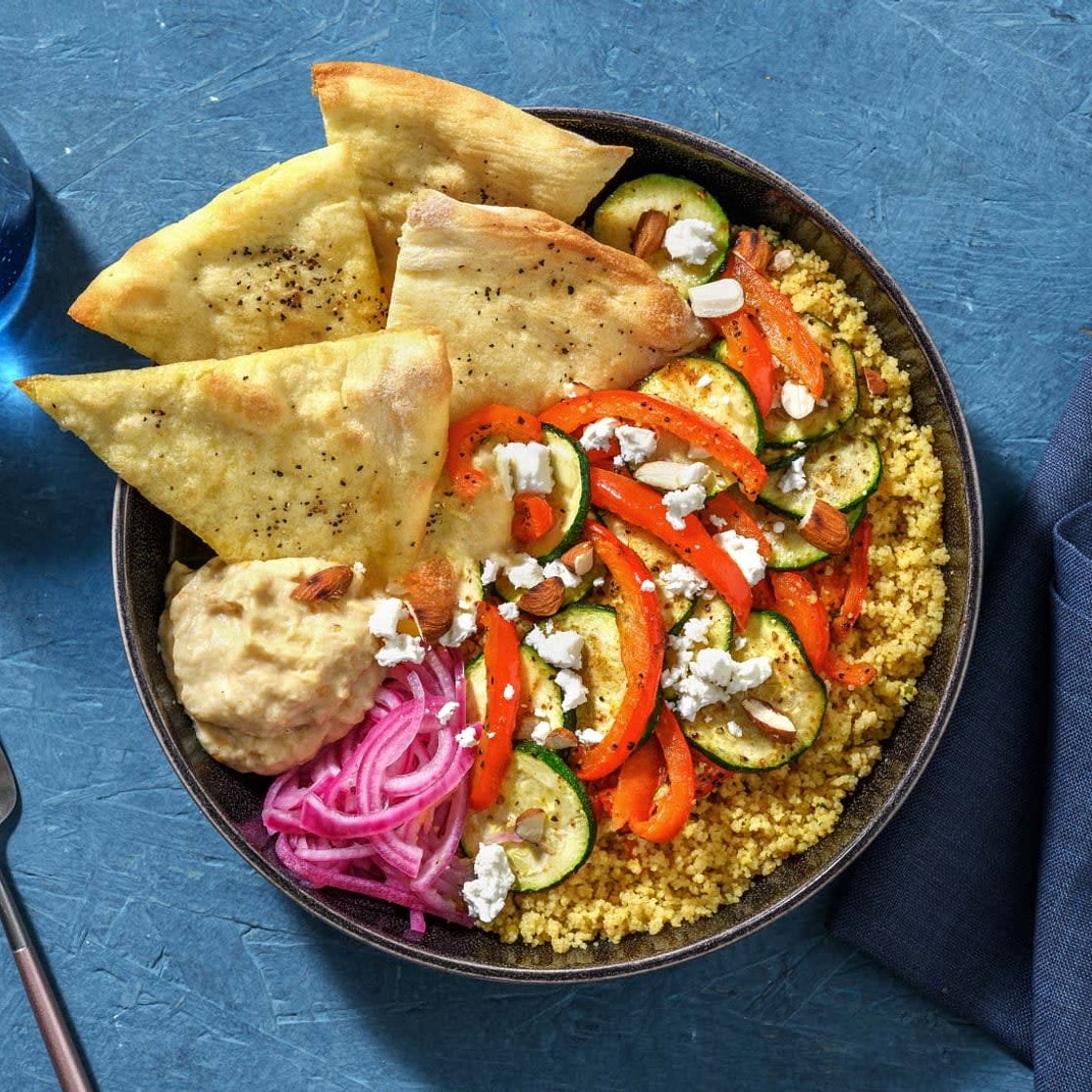 Bowl au baba ganoush avec semoule et fromage grec, oignon rouge mariné, légumes rôtis et amandes