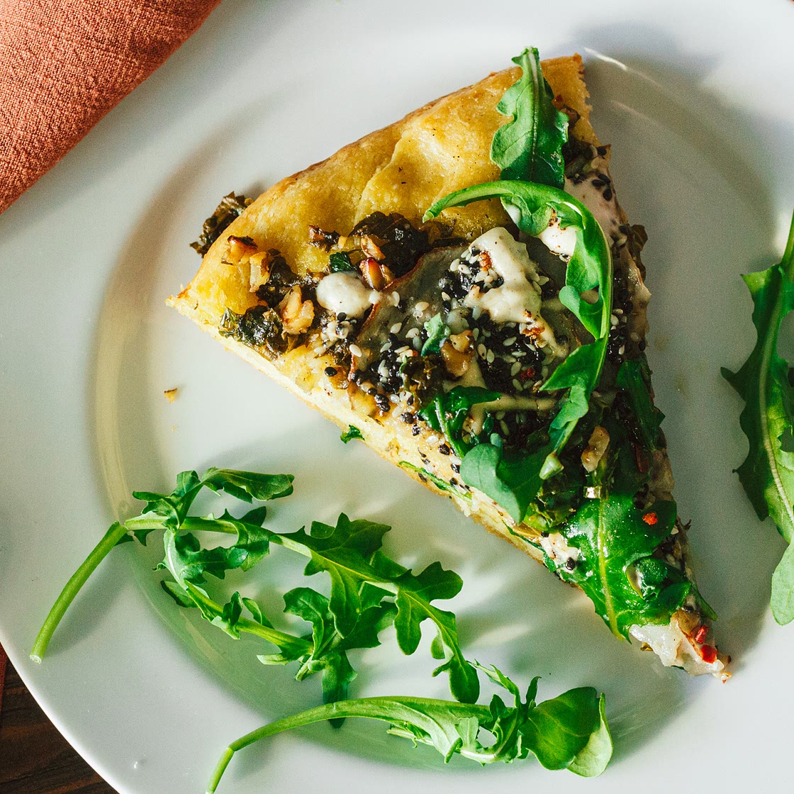 Crispy Seasoned Potato Pesto Pizza with Cashew Mozzarella Cream and Arugula on an Herbed Crust