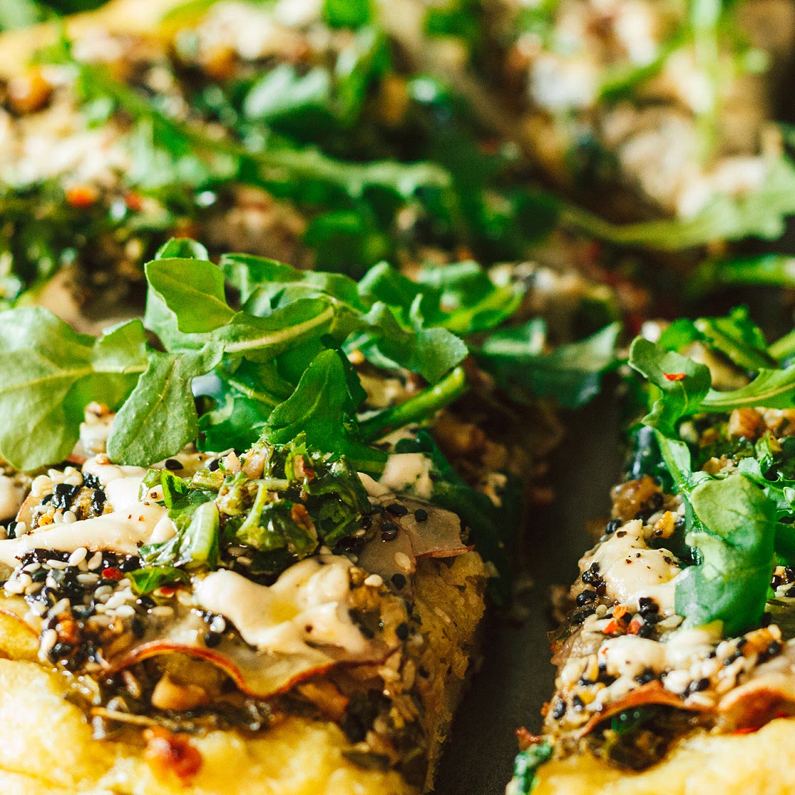 Crispy Seasoned Potato Pesto Pizza with Cashew Mozzarella Cream and Arugula on an Herbed Crust