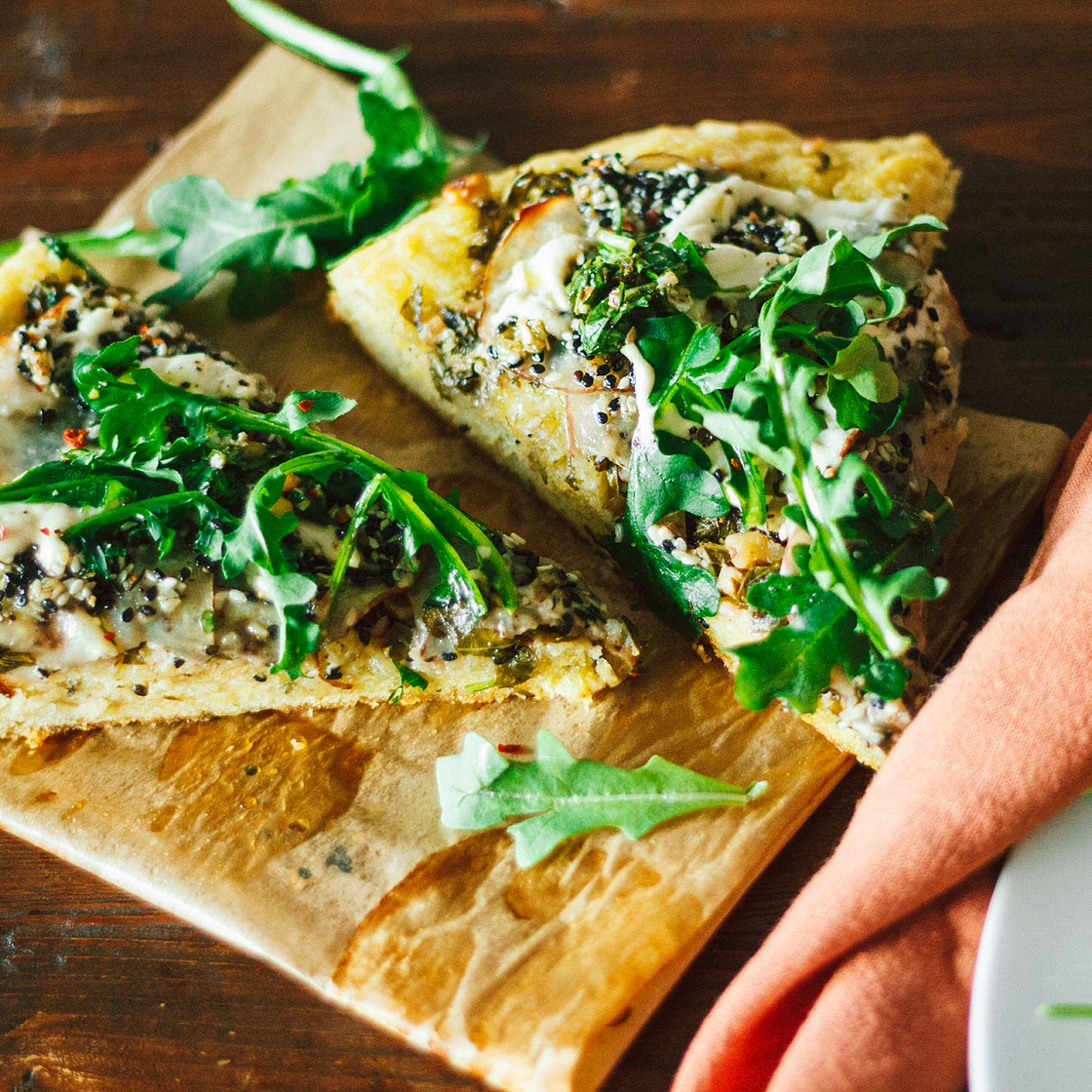 Crispy Seasoned Potato Pesto Pizza with Cashew Mozzarella Cream and Arugula on an Herbed Crust
