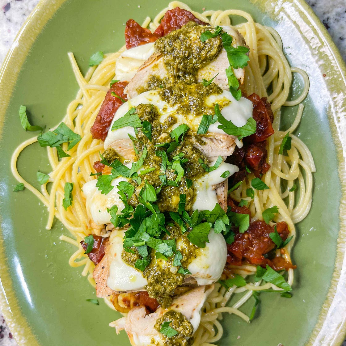 Mozzarella tomato pesto chicken over pasta