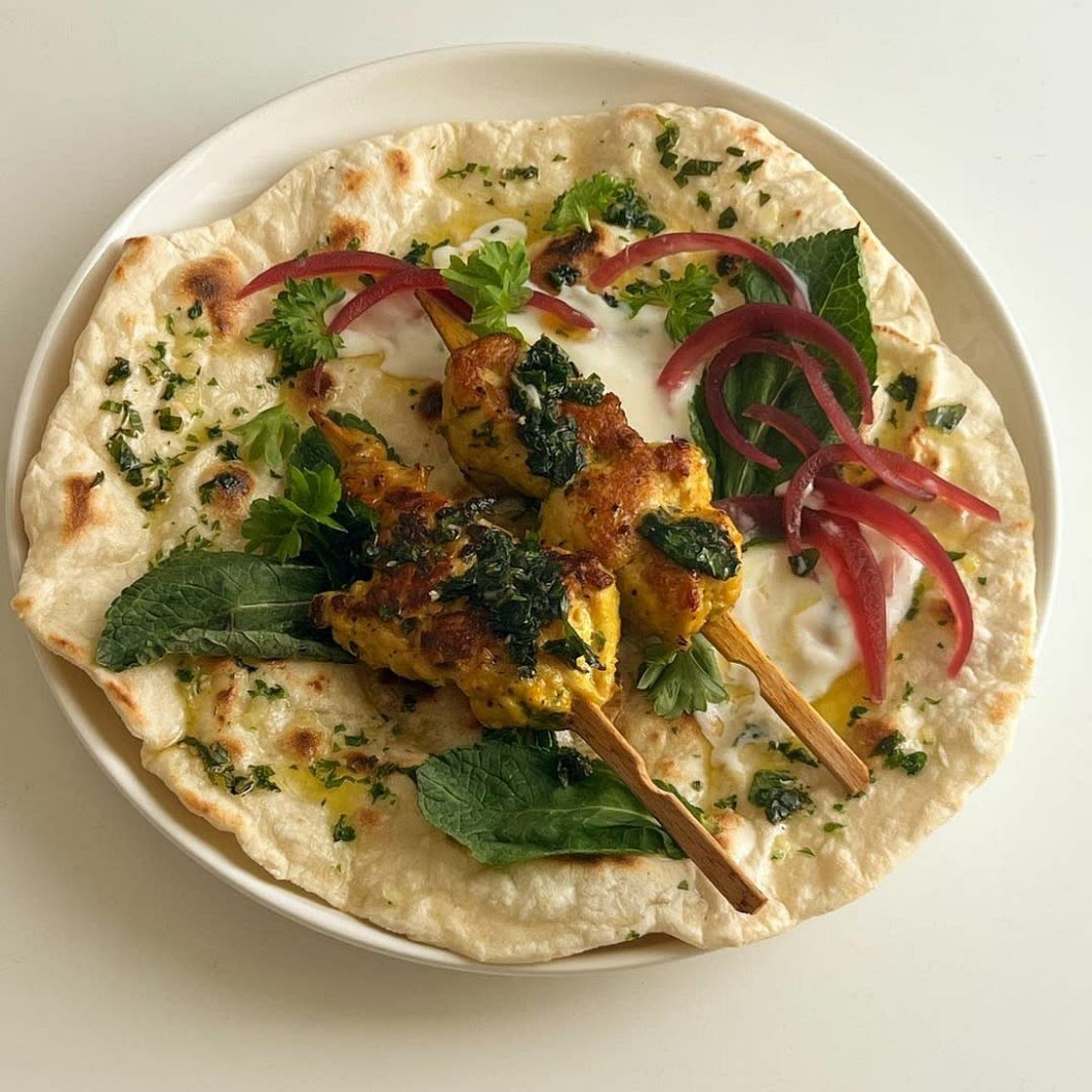 garlic herb flatbread with turmeric chicken skewers with mint leaves