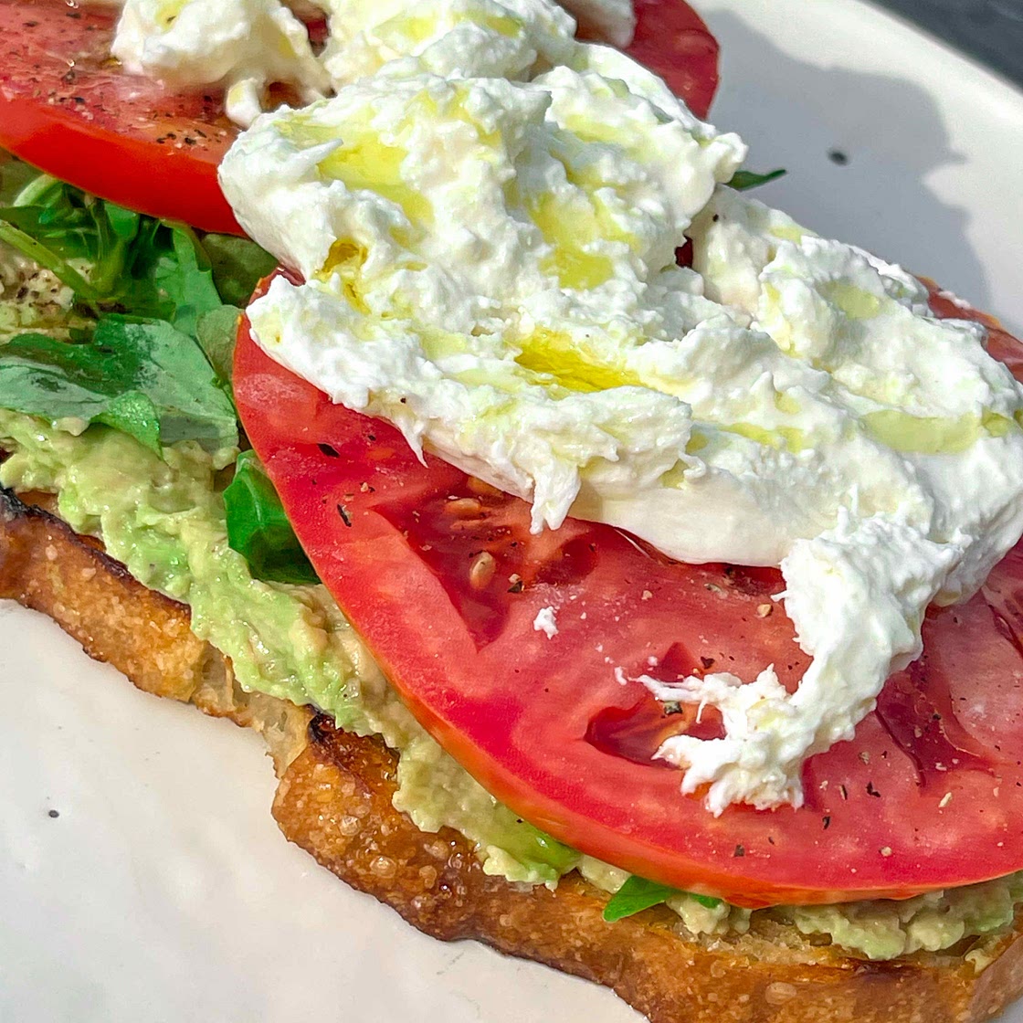 Avocado toast with tomatos and burrata.  
