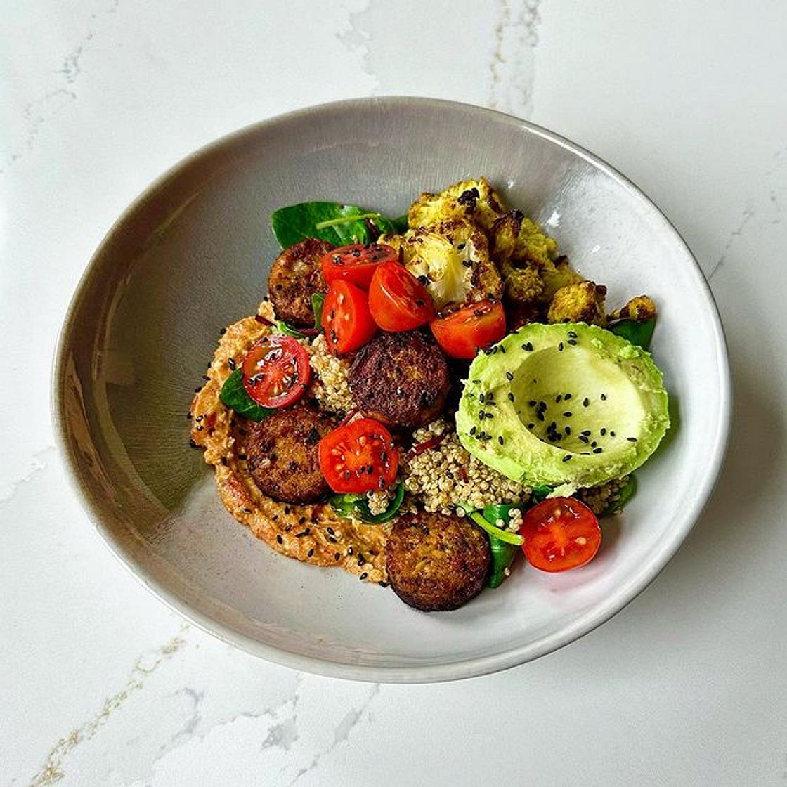 Quinoa falafel bowl met geroosterde paprika feta dip en kerriebl