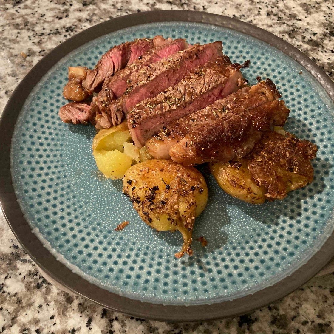 Cast iron seared steak over parmesan crusted smashed potatoes 