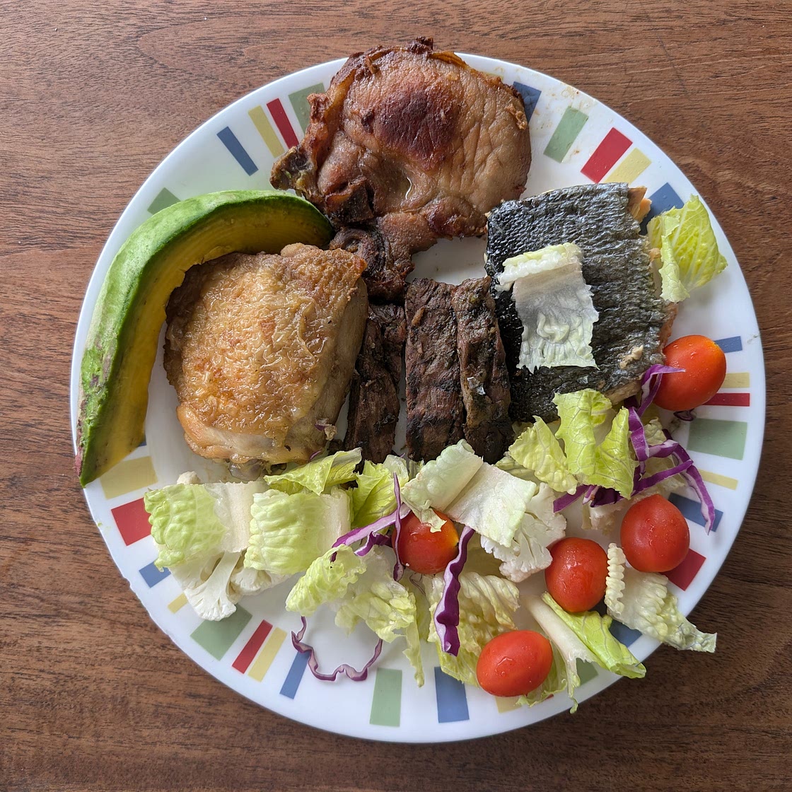 Pork chop, chicken thigh, salmon, and churrasco with avocado, lettuce, baby tomatoes, and purple onion