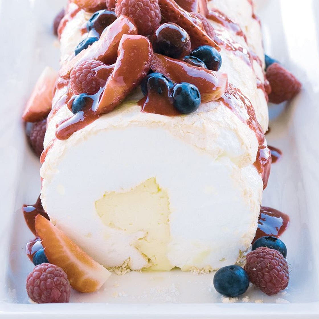 Soft pavlova roll with liqueur mascarpone and berry compote