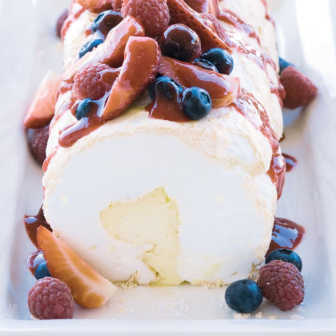 Soft pavlova roll with liqueur mascarpone and berry compote