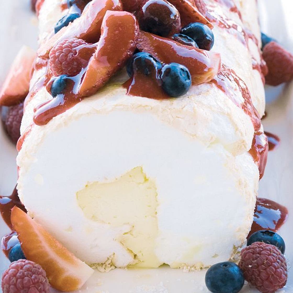 Soft pavlova roll with liqueur mascarpone and berry compote
