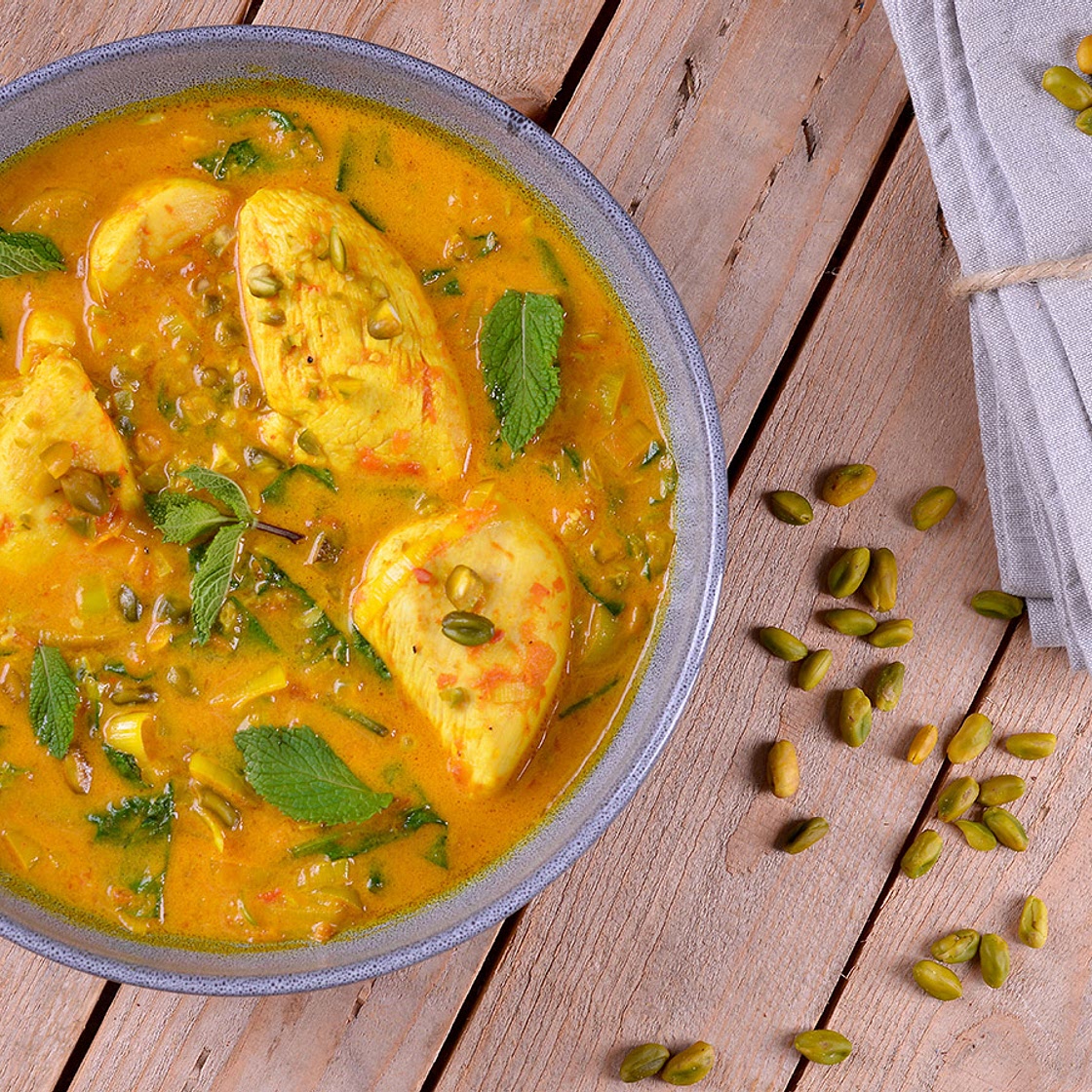 Pollo guisado con cúrcuma, hojas verdes y pistachos