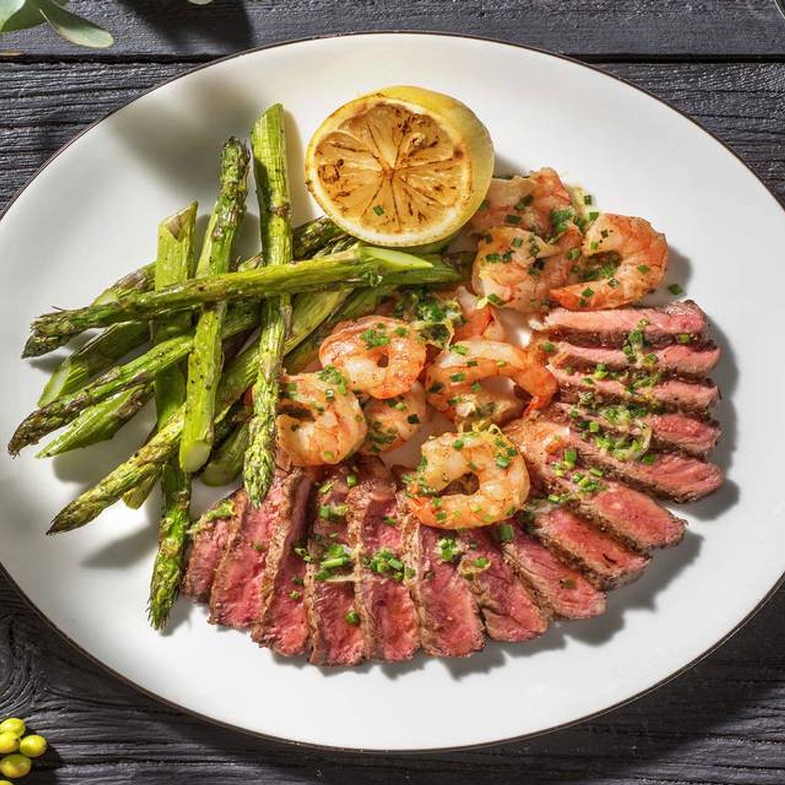 Surf and Turf: Sirloin Steak and King Prawns with Wedges, Asparagus and a Charred Lemon and Garlic Butter