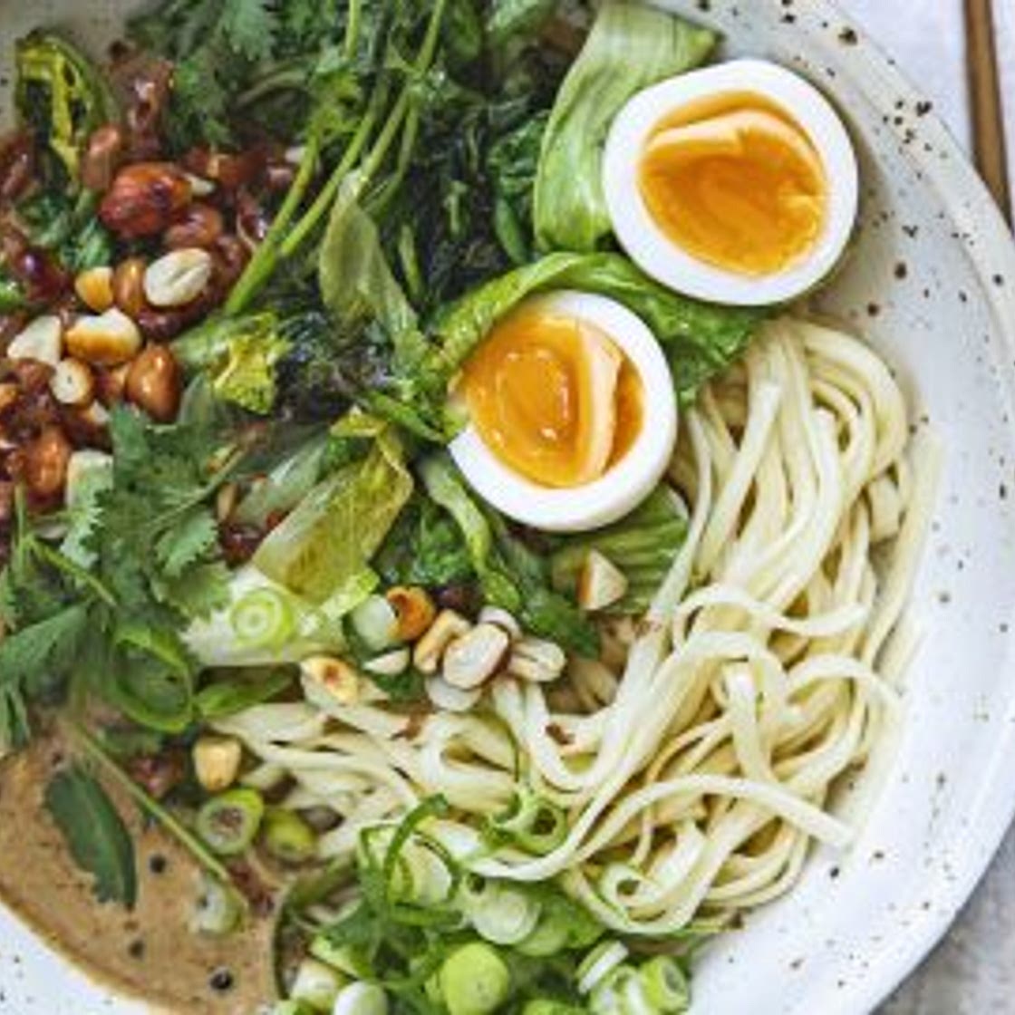 noedels met gewokte andijvie, tahin-sojasaus en pinda’s