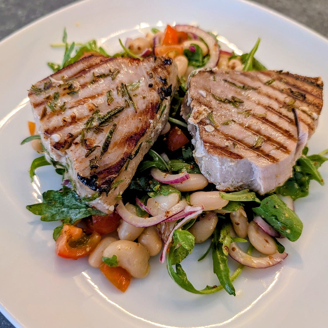 Griddled marinated tuna steaks with beans, tomato, rocket and red onion salad