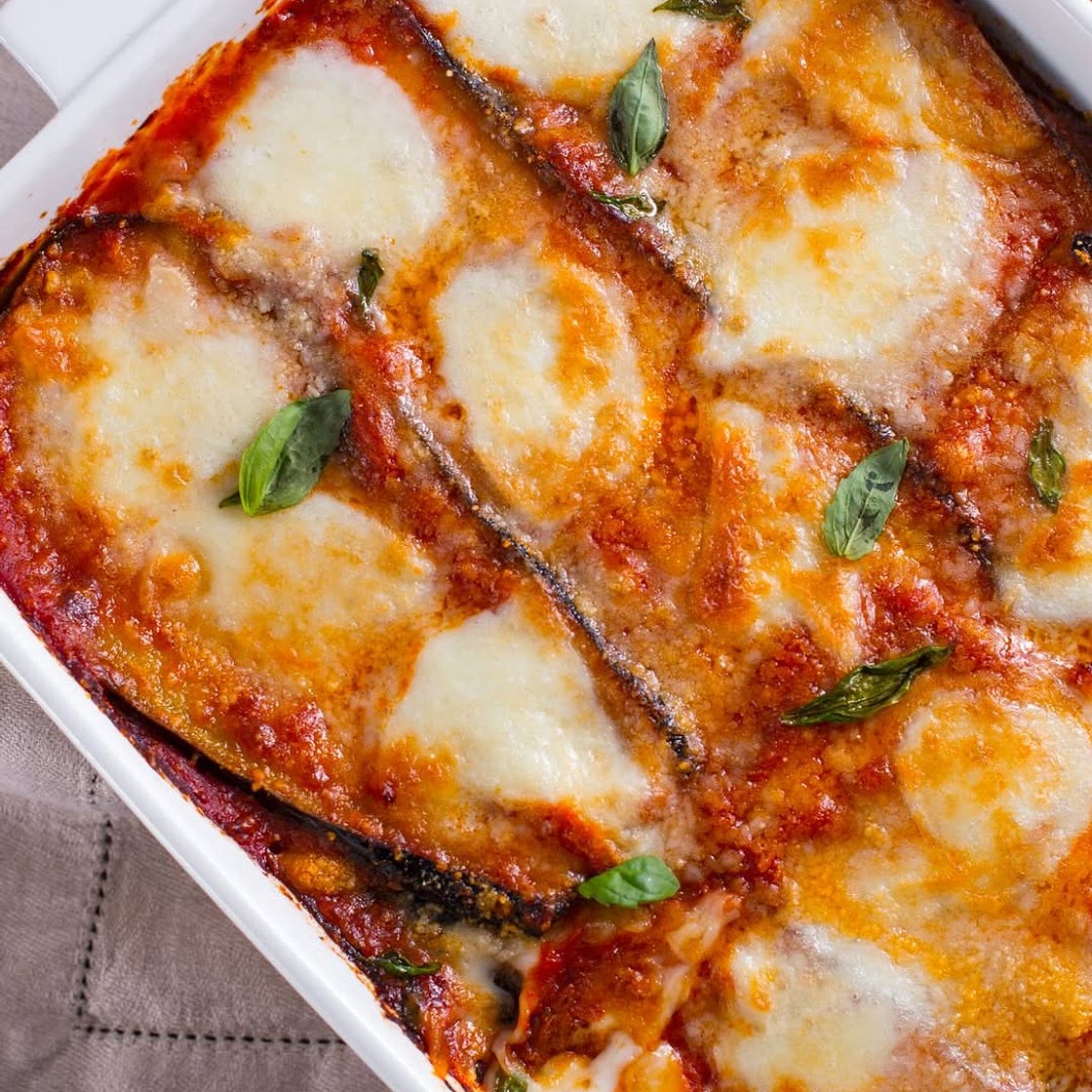 Parmigiana di Melanzane ovali nere 1,7 kg Passata di pomodoro 1 kg Mozzarella 500 g Parmigiano Reggiano DOP (da grattugiare) 150 g Cipolle dorate 1 Basilico q.b. Olio extravergine d'oliva q.b. Sale fino q.b. Per friggere: Olio d