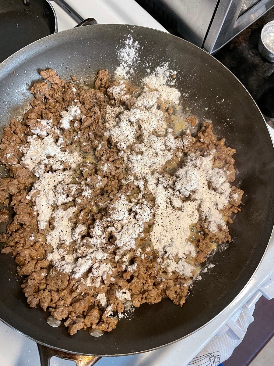 If your vegan sausage didn’t render much oil, add 2-3 tablespoons of vegan butter or a neutral oil to the pan. This is to make the roux - you want approximately 4 tablespoons of fat to match the 1/4 cup of flour. Sprinkle the flour and pepper over the sausage and cook, stirring constantly, until the flour has been absorbed by the fat and has gathered its flavors close, approximately 5 to 7 minutes.