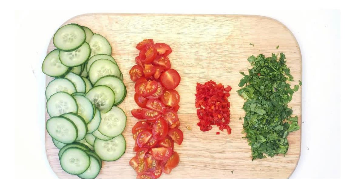 Meanwhile, slice the cucumber finely. Roughly chop the cherry tomatoes. Cut the red chilli[es] in half lengthways, deseed (scrape the seeds out with a teaspoon) and chop finely. Chop the coriander finely, including the stalks. Wash the rocket, then pat it dry with kitchen paper.