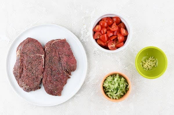 Prepare the Ingredients
Quarter tomatoes. Trim cucumber. Grate on large holes of box grater. Mince garlic. Pat steaks dry, and season both sides with remaining garlic salt and 1/4 tsp. pepper.