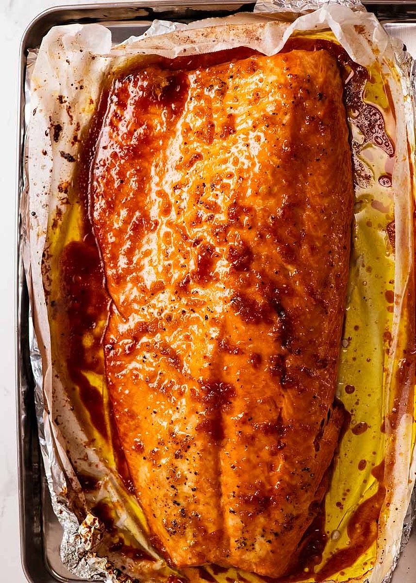 Immediately transfer to serving platter using the paper overhang (otherwise the salmon will keep cooking on the tray), either lifting or sliding it off. And here’s how to remove the foil and paper from under the salmon – just tear and slide!