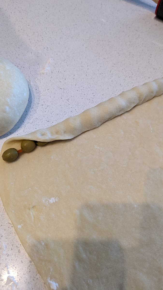 Make a line of Olives 1 cm from the top of the dough then make a wrap around the line of Olives