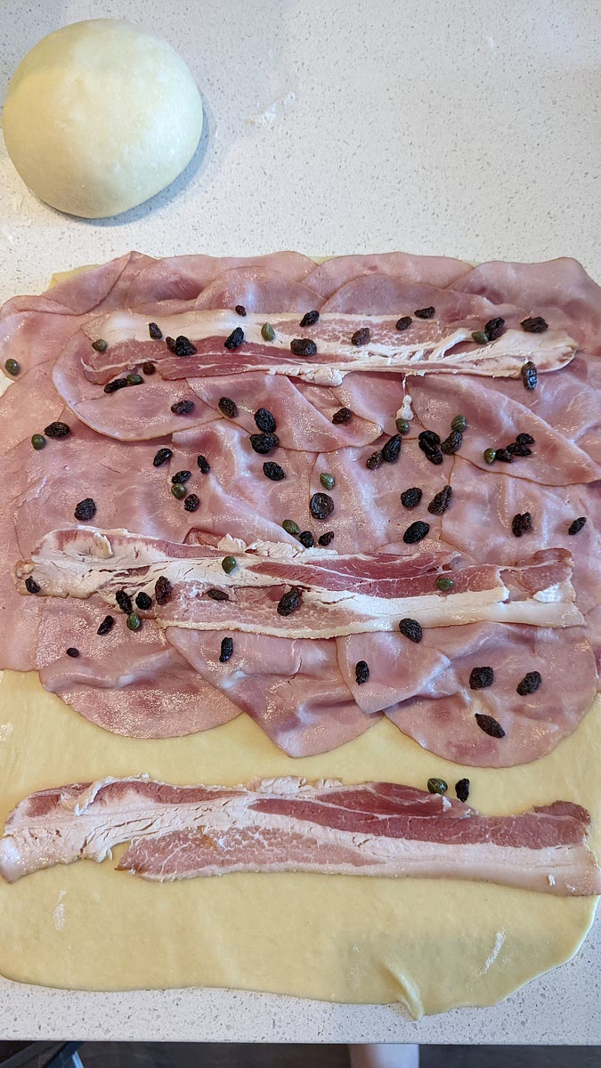 Add raisins and capers spreaded across the whole dough