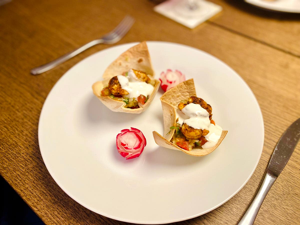 Assemble the cups by placing a spoonful of the avocado salsa in the toasted cup. Place 2 pieces of shrimp on top, followed by a dollop of sour cream and served with radish roses you made.