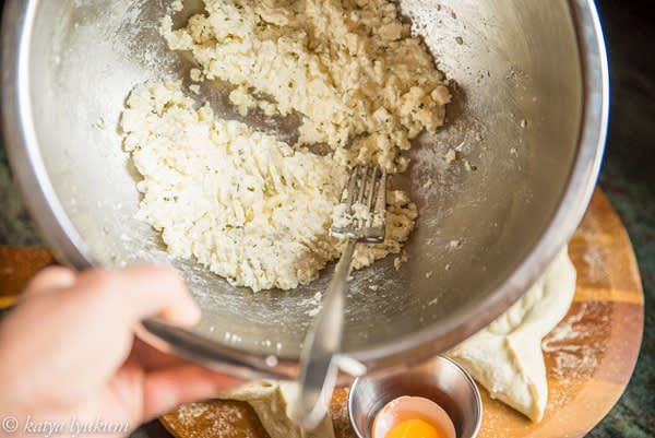 Prepare the filling. If using burrata, score it on one side and place it on the dough with soft curds up. If using a combination of two types of cheese, crumble both of them. Season the mixture to your taste. It should be savory. Right before baking, separate egg yolks and whites. Mix egg whites (not all of them, see the list of ingredients) into the cheese filling. Reserve the egg yolks, one per portion.