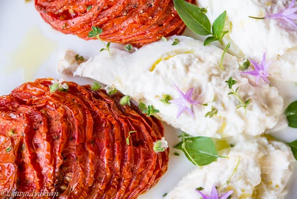 Place them on a baking pan, flatten slightly, and roast for an hour (middle rack). When roasted, brush tomatoes with olive oil. Let them cool to room temperature and refrigerate for at least 1 hour. Roasted tomatoes can be cooked in advance. Serve cold with sliced burrata sprinkled with olive oil and fresh herbs. Fresh crusty bread is a must.