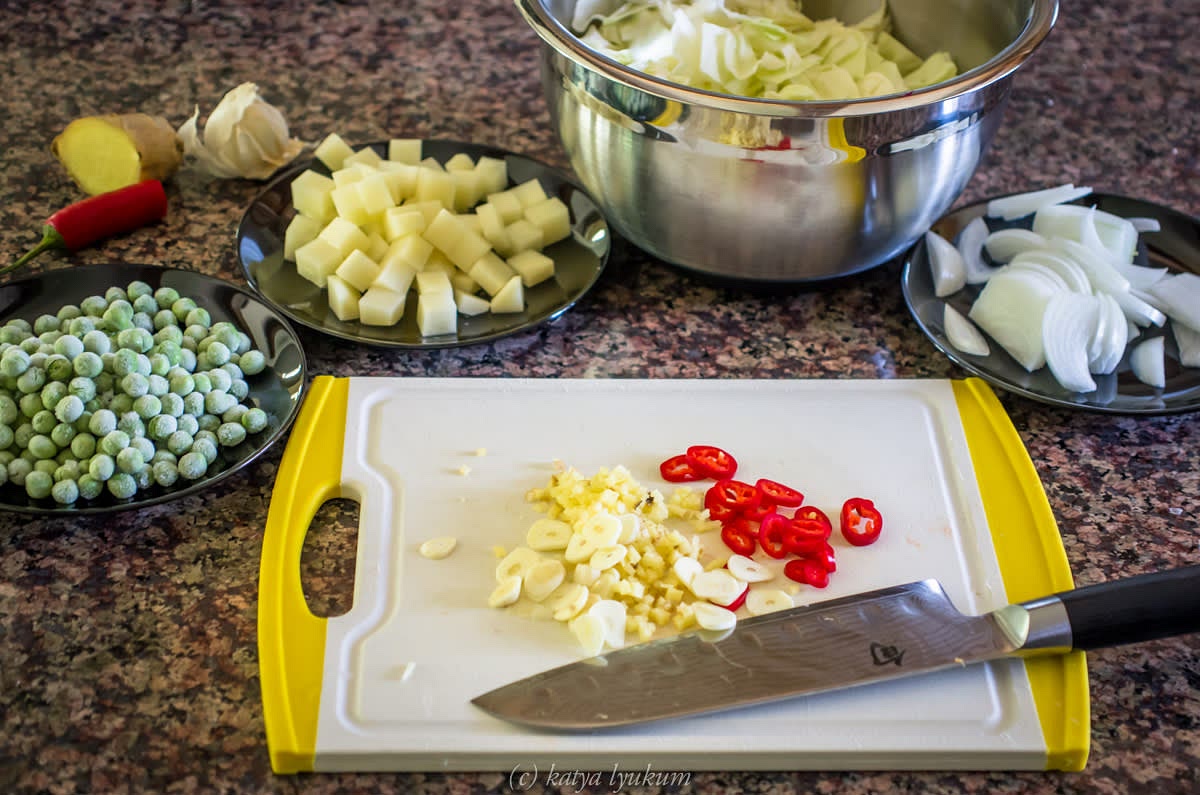 Clean, peel, and dice potatoes. Keep them in cold water. Separate and dice cabbage leaves. Peel and dice onions, ginger, and garlic. Cut green chile in half, remove seeds and membranes, dice. Measure other ingredients and group them.