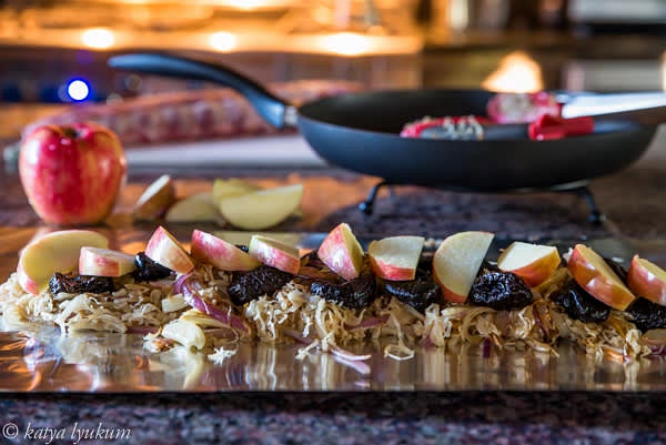 Core and slice apples. Peel garlic cloves. Arrange equally distributed dry plums, garlic, and apple slices on top of the cabbage. Sprinkle with some thyme, pepper, and salt.