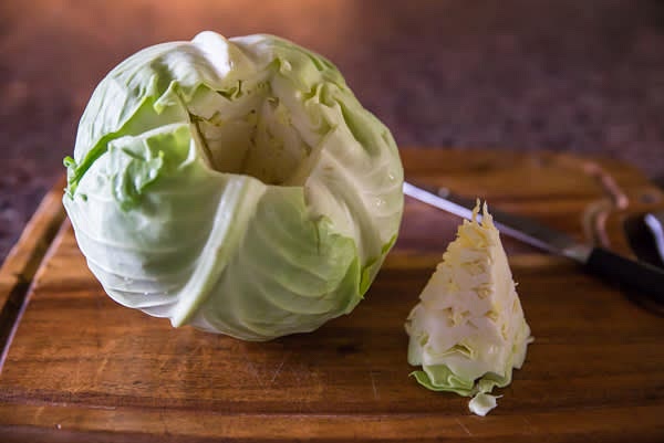 Place a large pot half-filled with water and boil on high heat. Core the cabbage head. Remove green and damaged outer leaves.