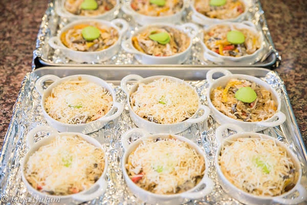 Preheat oven 400F. Prepare 12+1 (control portion) 6oz ramekins. Mix chicken and vegetables with half of the sauce and spoon a portion into every ramekin. Top with sauce and grated cheese.