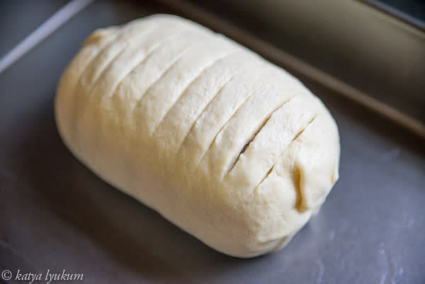 Finish the roll, place it so the end of the dough is under, and score the top to the layer of mushrooms. Make an egg wash and brush the top.