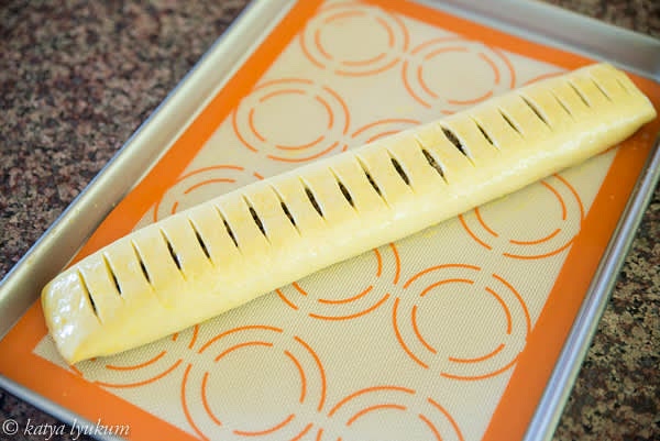 Roll two ends towards the middle. Secure the filling and carefully roll it upside down to the lined baking pan. Score the top making 1/2" intervals and cutting through to the layer of mushrooms. Make an egg wash and brush the top.