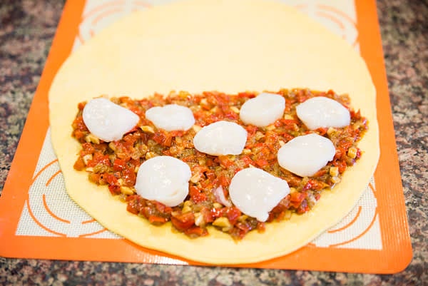 Roll each portion of dough ~10"D. They will be either bottom and top parts of one round empanada or two empanadillas. Spread a generous amount of poached vegetables and place sliced scallops on top.