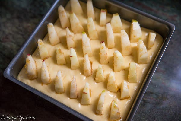 Pour the batter into the baking pan and arrange the apple slices vertically. Their tops will be above the surface of the dough. When the batter rises during the baking, it will cover apples.