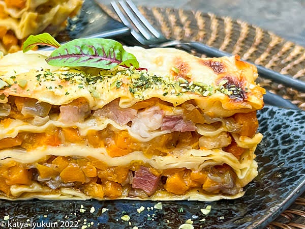 Run the knife around the edges of the baking dish. Flip the baking dish upside down to release the lasagne. The parchment should stick to the bottom of the baking dish. If it is attached to the bottom of lasagna instead, peel it off. Slice lasagne into the portions and serve.
