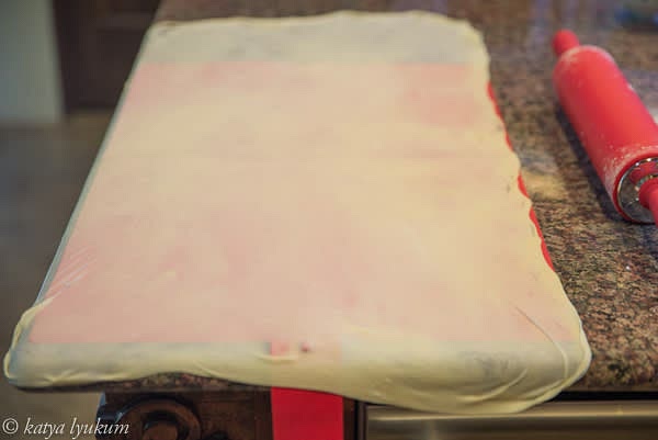 Slowly peel the dough off the working surface, carefully pick it up with the back of your hands, and transfer it to the silicone mat (or tablecloth). Continue stretching the dough on the silicone mat to reach the final size (15"x36").