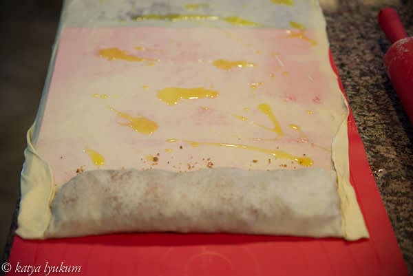 Using your hands, do the first fold of the dough with bread crumbs. Continue rolling by lifting the shorter edge of the silicon mat to the end.