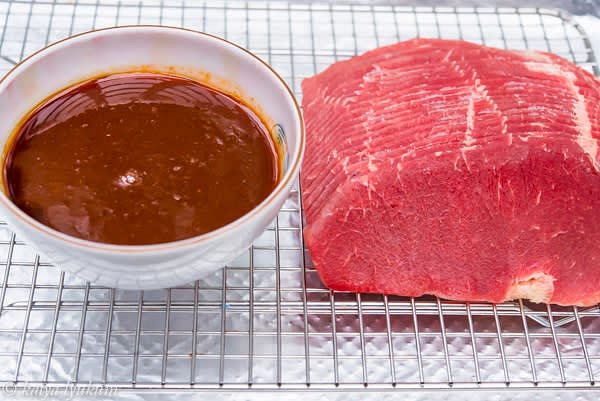 Defrost thinly sliced frozen beef in a refrigerator for a few hours. Timing depends on the amount of meat packaged together. Line a baking pan with foil to collect drippings. Place a heavy-duty roasting rack into the pan. Have marinade ready.