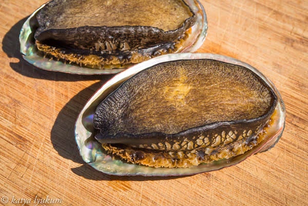 Place two large abalone in simmering ocean water for 2 minutes. Remove and let them cool to room temperature. Repeat with the rest of the abalone.
