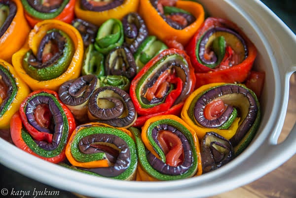 Layer slices of vegetables, starting with pepper on the bottom and finishing with a piece of tomato on the top. Roll them together and place them vertically into the baking dish.