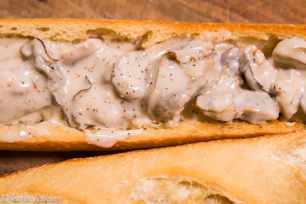 Add cream and cook the sauce down to thicken for another 2-3 minutes, simmering and stirring. Taste and adjust seasoning. Turn the heat off and combine with oysters. Fill the toasted baguette halves and serve warm.