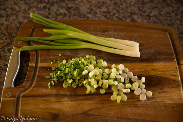 Wash, trim, and slice scallions.