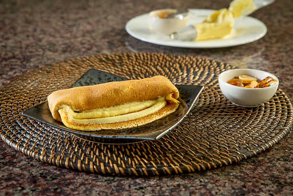 Arrange 2-3 tbsp of apple confiture in a raw and roll the crepe. Place it on a serving plate and tuck the edges. Pipe a layer of creme brulee on top of the roll. Repeat plating the rest of the crepes.