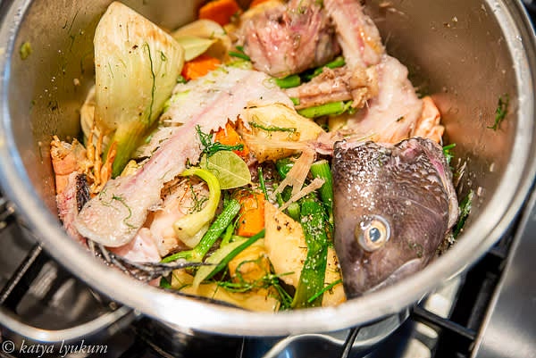 Heat 1/3" deep olive oil in a large pot. Add crustacean heads and shells and cook until bright orange for 5 minutes. Add root vegetables and saute for another 5 minutes until sweet and aromatic. Add tomatoes and cook for another 5 minutes. Flambe with Pernod/Pastis. Add fish heads and bones and fill the pot with wine and cold water to cover solids plus 2". Add spices, herbs, green tops bunches, and orange zest and juice. Bring to boil, reduce the heat to medium-low and let simmer for 45 minutes.